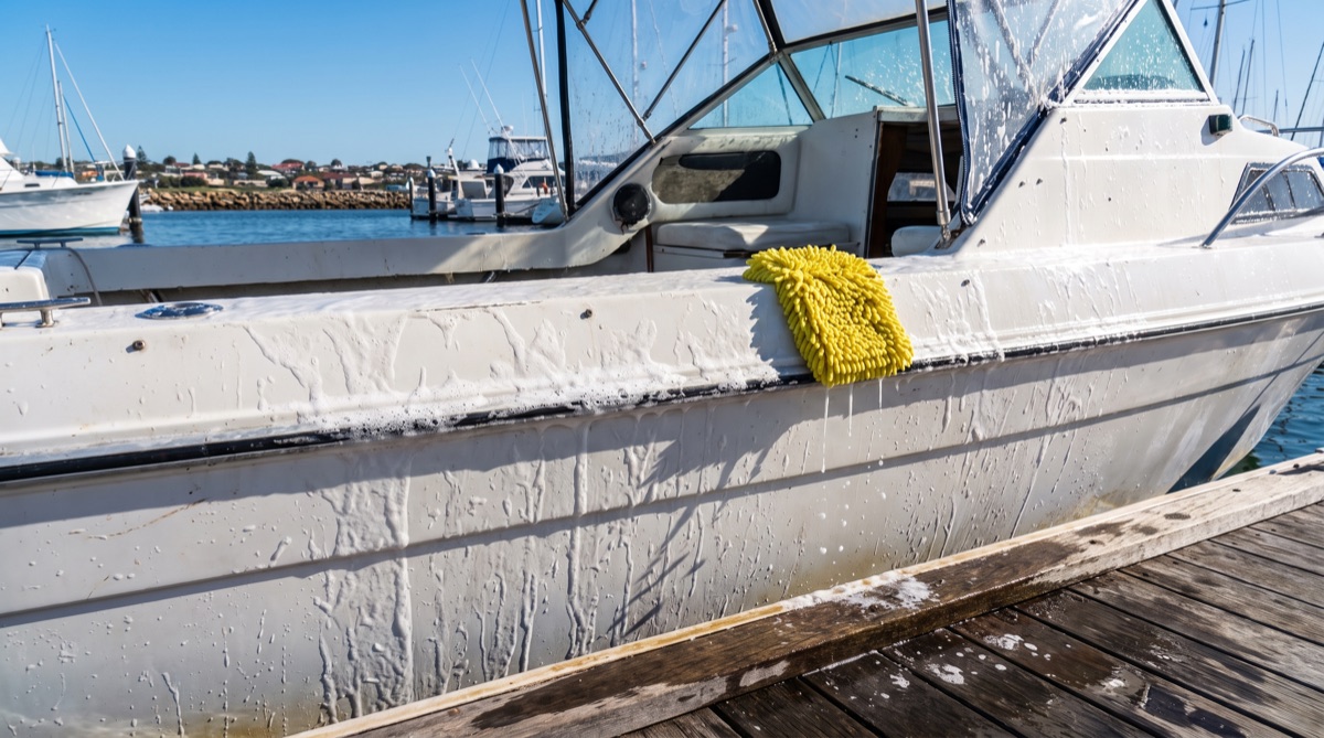 Soap suds on a boat hull mid-wash at the jetty